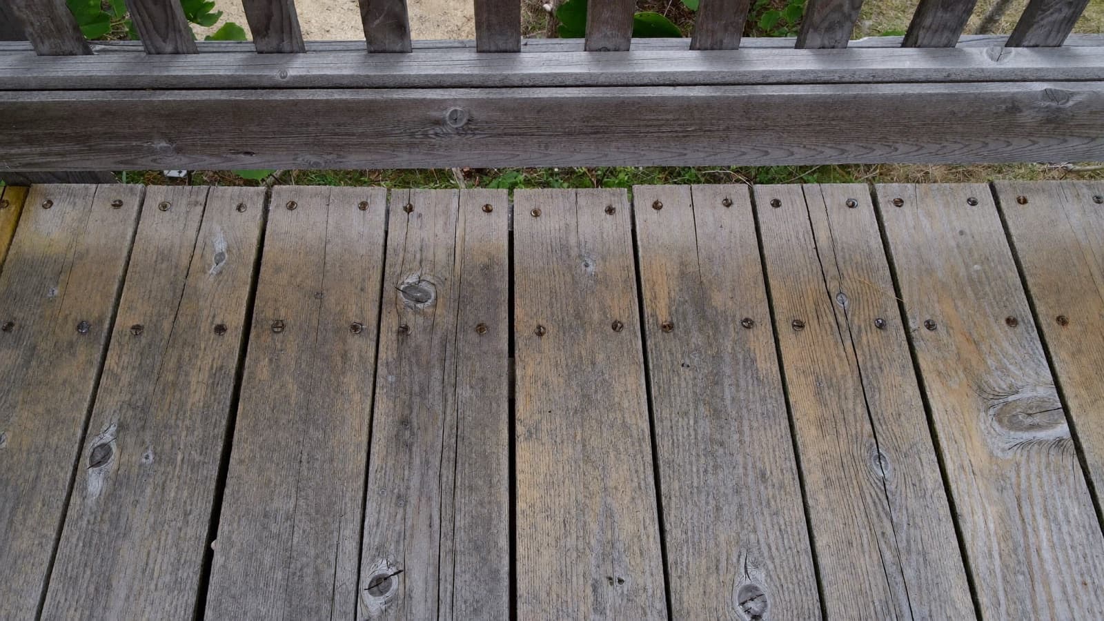Older wooden deck with worn boards and raised nail heads in need of repair